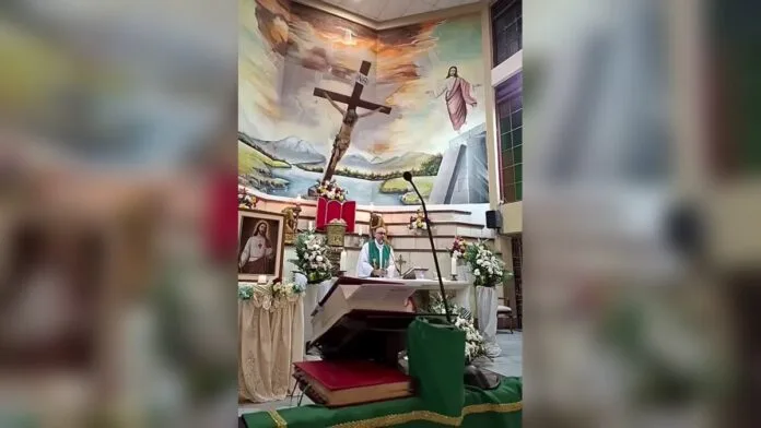Sacerdote Patricio Sánchez Molinari frente al altar mientras un enorme crucifijo de madera cae detrás de él durante una misa en Guayaquil.